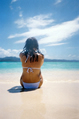 female in white bikini sitting on beach at paradise island