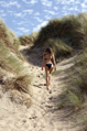 female in bikini walks into sand dunes