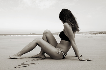 Woman in tie-side bikini reclines on beach