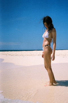 woman in white bikini standing on empty beach