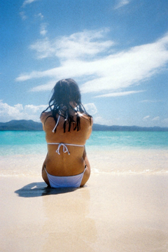 female in white bikini sitting on beach at paradise island