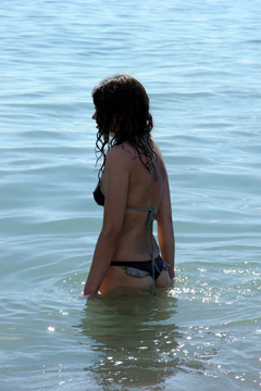 female in bikini wading through the sea