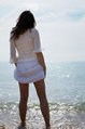 Woman paddles on the sea edge with white skirt pulled up