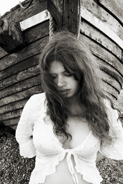 woman in white lace standing as figurehead at the bow of a boat