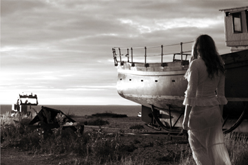girl in sheer white lace walks past fishing boat