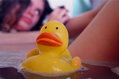 Rubber bath duck swimming past womans thigh in bath