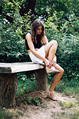 Female tying her sandals on a wooden bench