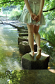 Girl in short denim skirt and sandals on stepping stones across a stream