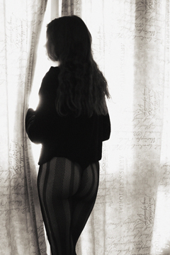 Woman in striped tights peeking through curtains